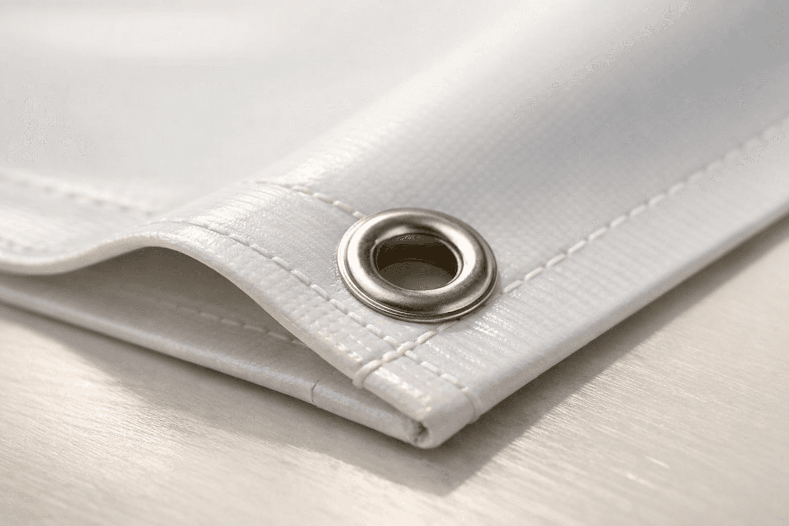 Close-up of banner hem, grommet, and vinyl edge detail under soft light